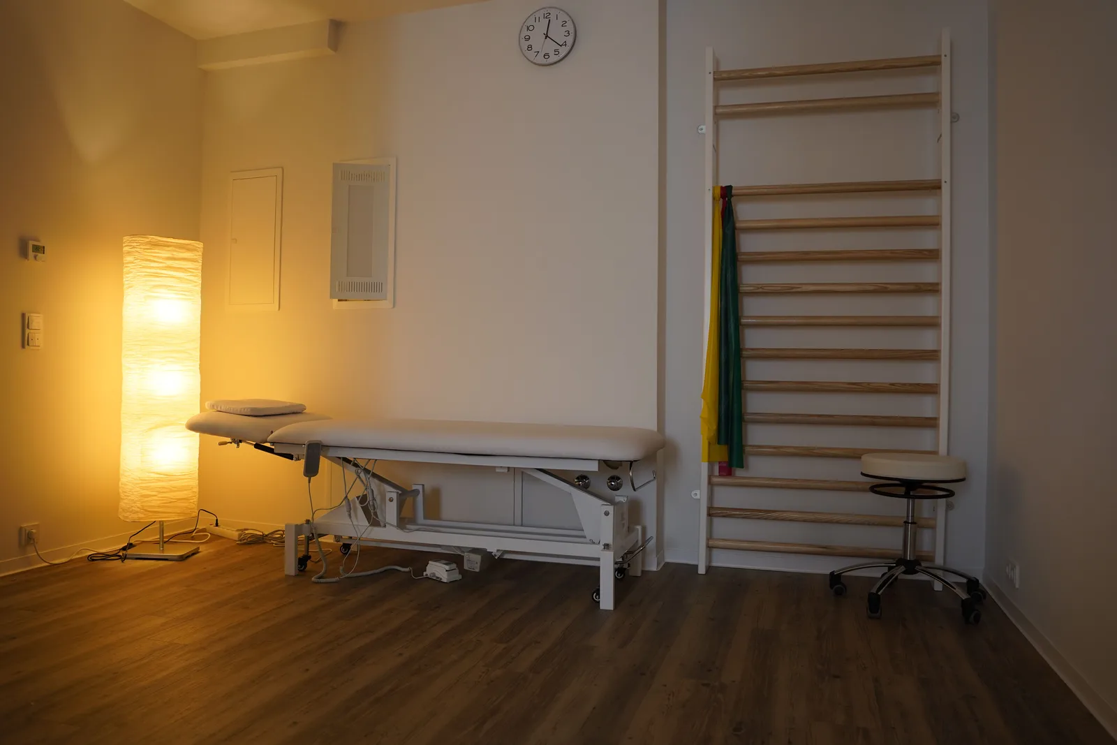 Warm beleuchteter Behandlungsraum mit Liege und Sprossenwand