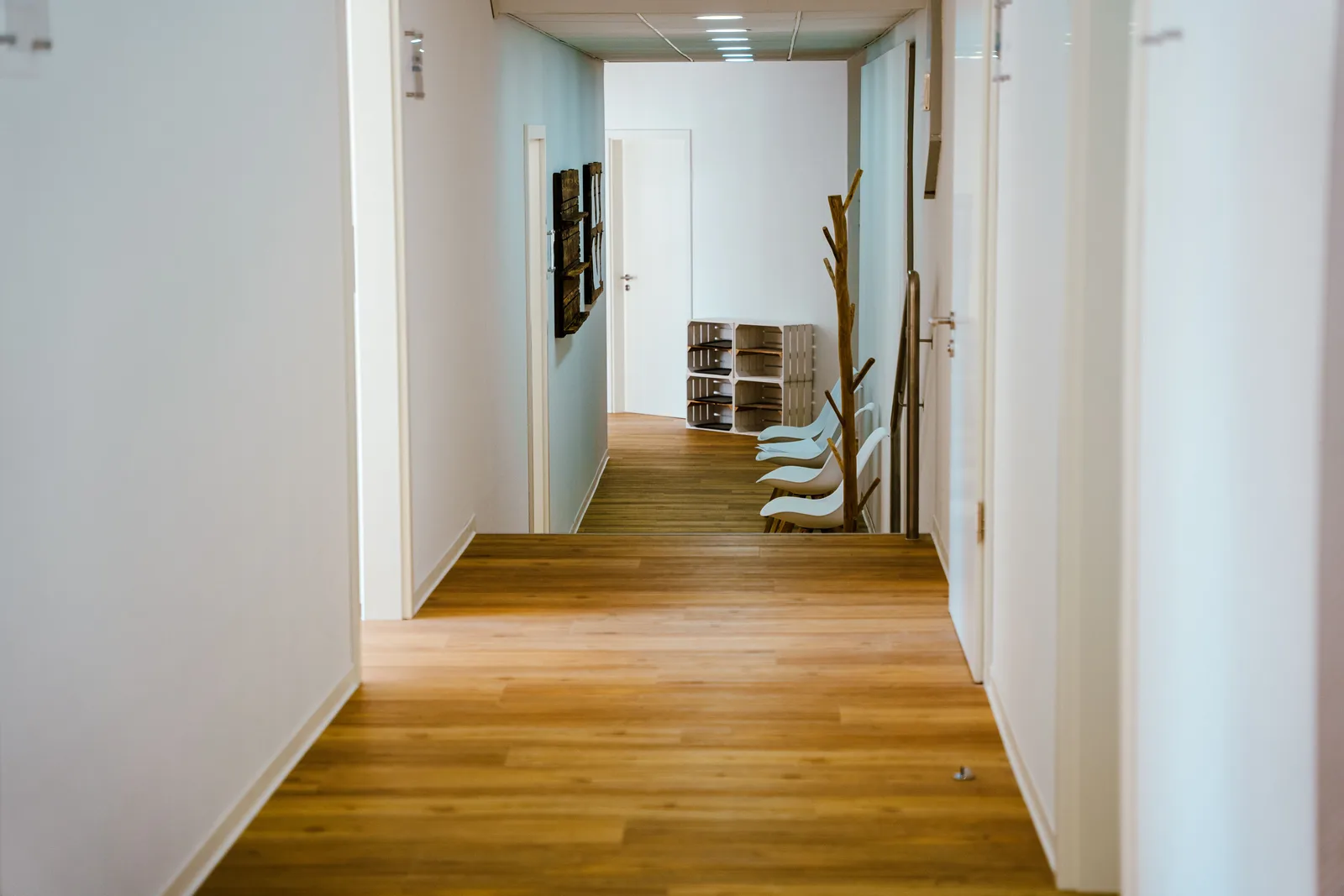 Heller Praxisflur mit Holzboden, Türen und Garderobenhaken