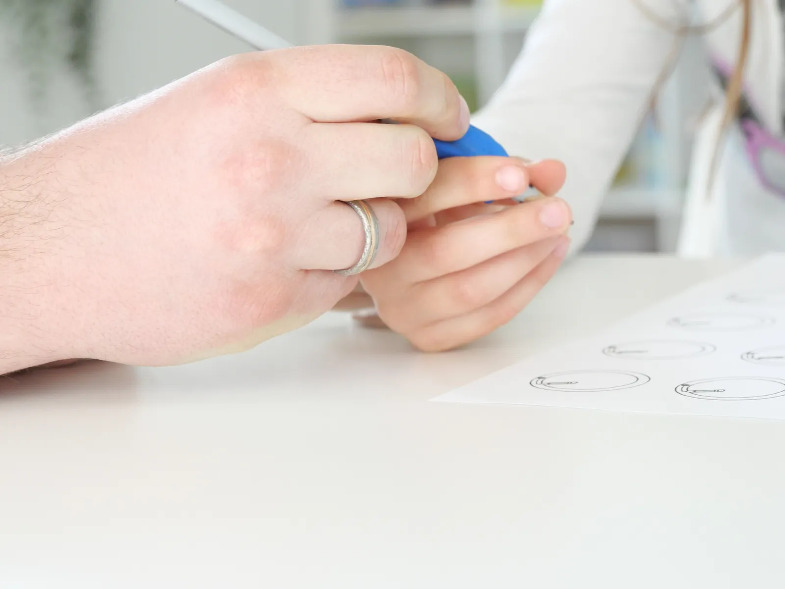 Feinmotorik-Übung: eine Hand führt einen Stift über ein Arbeitsblatt