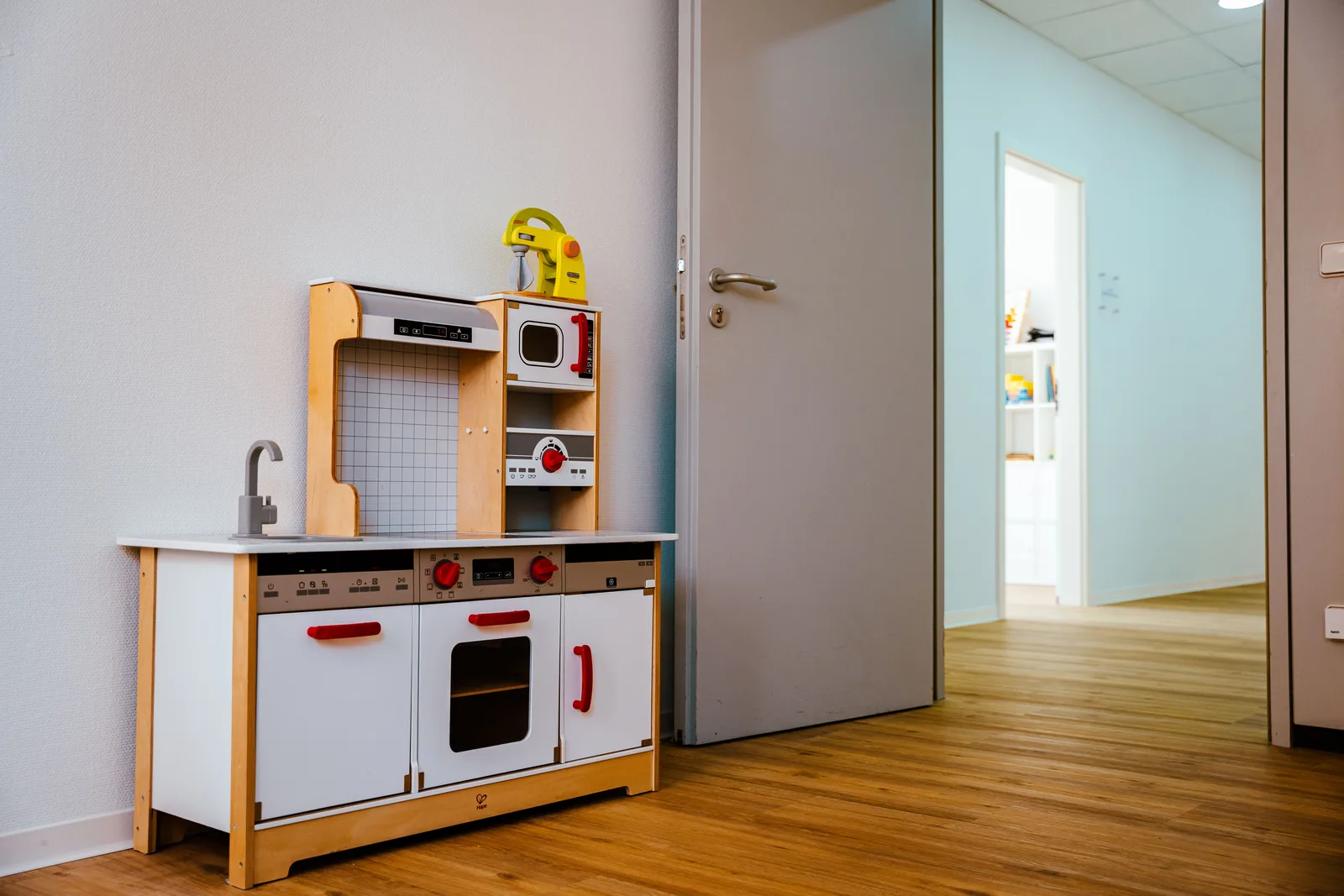 Kinderspielküche aus Holz in einem Therapieraum, Blick in den Flur