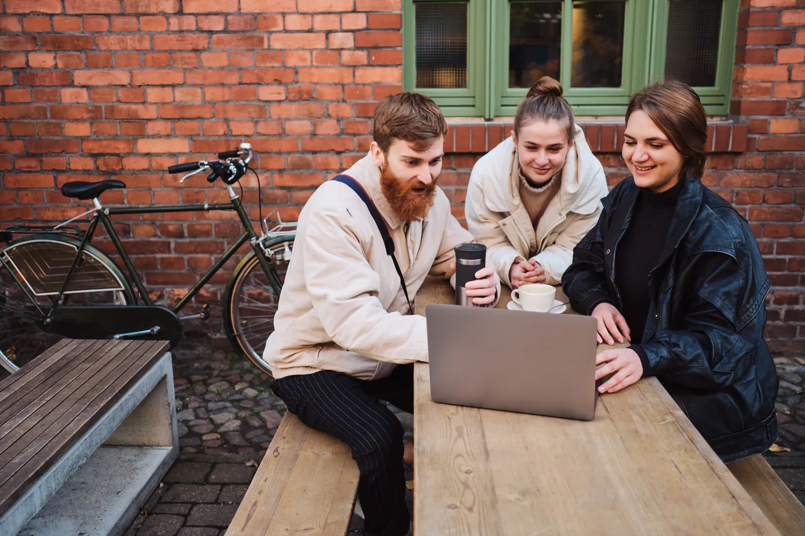 Zwei Therapeutinnen sitzen mit Laptop und Unterlagen an einem Cafétisch und planen einen Fortbildungszeitraum